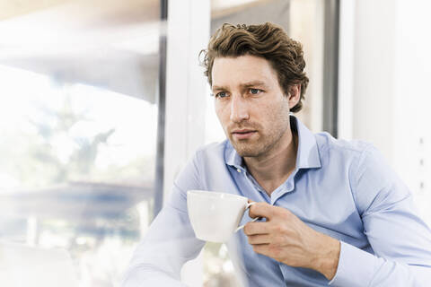 Mid adult man drinking coffee while sitting in office stock photo