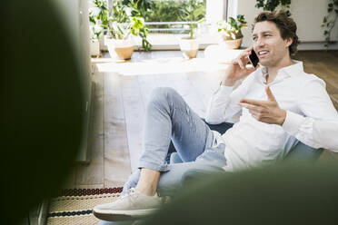 Mid adult using smart phone while sitting on chair at home - UUF21923