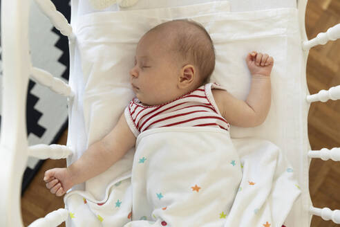 High angle view of baby girl lying down in crib at home - SKF01599