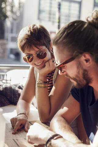 Mittlerer erwachsener Mann und junge Frau schauen sich die Speisekarte an, während sie in einem Cafe sitzen, lizenzfreies Stockfoto