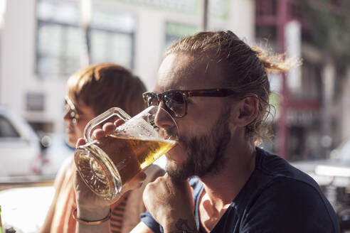 Mid adult man drinking beer while sitting in cafe - AJOF00382