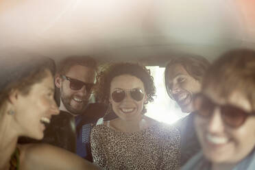 Lächelnde männliche und weibliche Freunde im Auto sitzend während einer Autoreise - AJOF00399
