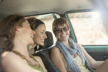 Lächelnde Freundinnen im Auto sitzend auf einer Autoreise - AJOF00400