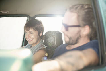 Lächelndes Paar im Auto während einer Autoreise - AJOF00404