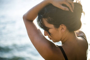 Young Latina Woman relaxing by the ocean at golden hour in summertime - CAVF89787