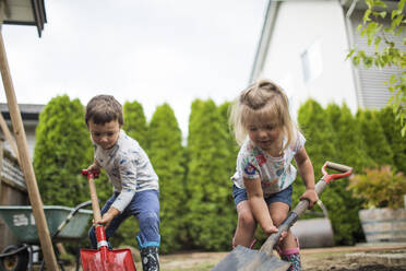 Bruder und Schwester graben in ihrem Hinterhof und helfen dem Vater. - CAVF89789