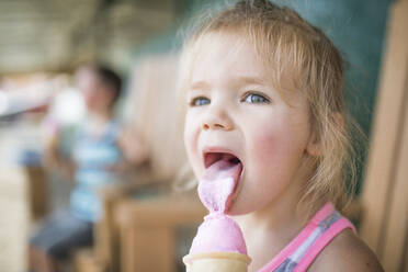 Junges süßes Mädchen leckt fröhlich rosa Eiscreme an einem Sommertag. - CAVF89792