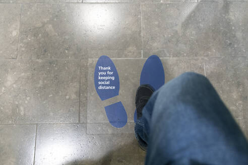Woman stepping on floor sticker written Thank You For Keeping Social Distance on it - CHPF00689
