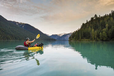 Father paddling inflatable boat with son on lake. - CAVF89899