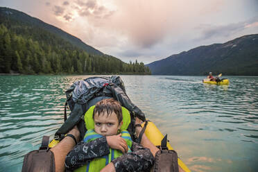 Junge mit mürrischem Gesicht auf einem See während einer Paddeltour - CAVF89903