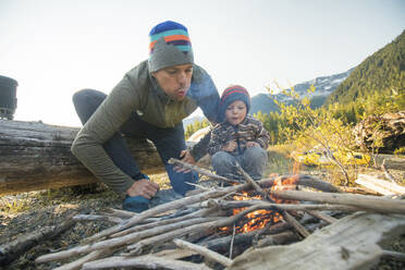 Father and son work together to start a fire at wilderness campsite. - CAVF89906