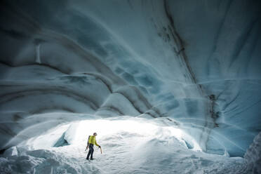 Eiskletterer blickt auf die Decke einer Gletschereishöhle in Kanada. - CAVF89920