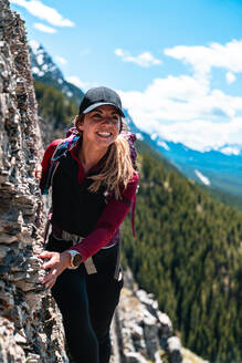 Hiker Smiling on Mountain Ridge High Above Valley Bellow - CAVF89942