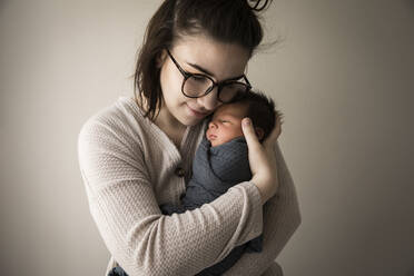 Modern Millennial Hipster Mom Snuggles Swaddled Newborn Baby Son - CAVF89962