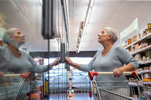 Kaukasische ältere Frau mit weißen Haaren kauft im Supermarkt ein - CAVF89975