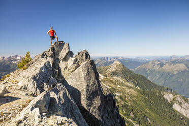 Backpacker stands on summit of mountain after a long day of hiking - CAVF89980