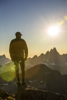 Silhouettenansicht eines Wanderers auf einem Berggipfel, der eine malerische Gegend erkundet - CAVF89985