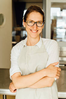 Portrait of female chef in glasses and apron smiling at camera - CAVF90005