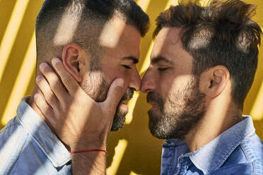 Homosexuelles Paar steht von Angesicht zu Angesicht gegen eine gelbe Wand - VEGF03038