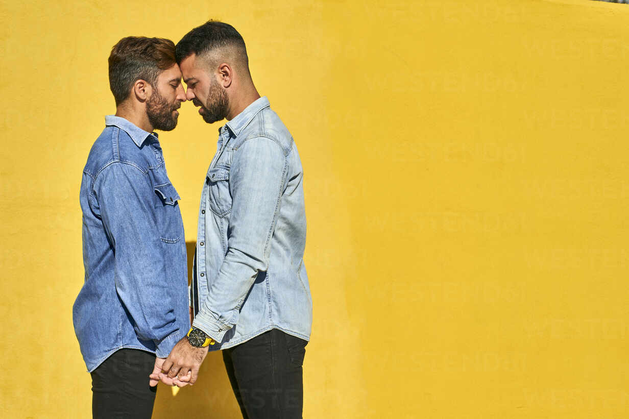 Schwule Männer Halten Hände Während Sie Mit Dem Gesicht Gegen Die Gelbe Wand Stehen 