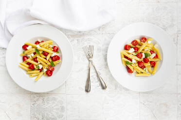 Zwei Teller mit vegetarischer Pasta mit Mozzarella, Kirschtomaten und Basilikum - LVF09052