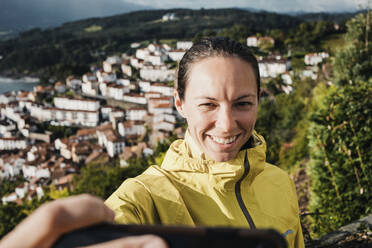 Lächelnde Frau nimmt Selfie durch Handy während der Ferien - DMGF00206