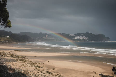 View of rainbow at beach seen during rainy season stock photo