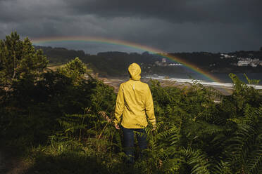 Rear view of woman wearing raincoat during rainy season - DMGF00220