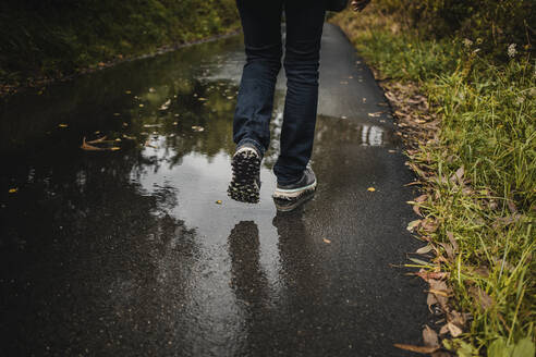 Beine einer Frau, die während der Regenzeit auf einem nassen Fußweg geht - DMGF00224