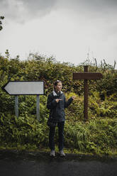 Contemplating woman gesturing while standing against plants during rainy season - DMGF00226