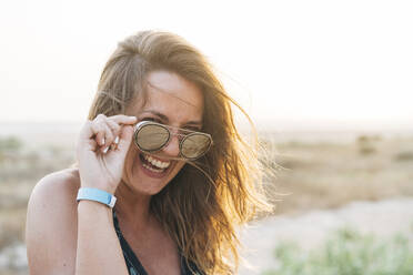 Fröhliche schöne Frau mit Sonnenbrille im Urlaub - DAMF00612