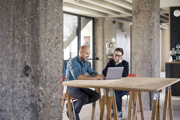 Business people working on laptop while sitting by table at office - MOEF03466