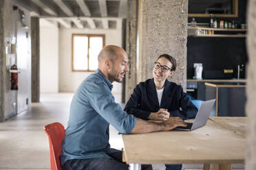 Geschäftsleute, die im Büro mit ihrem Laptop diskutieren - MOEF03468