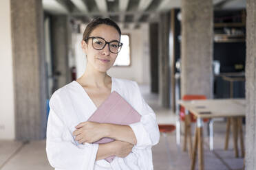 Businesswoman holding digital tablet while standing at office - MOEF03518