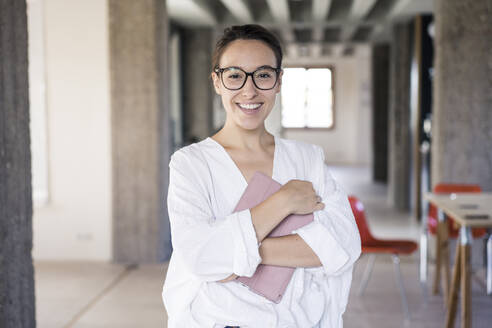 Businesswoman with digital tablet smiling wile standing at office - MOEF03521