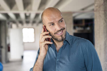 Businessman talking on mobile phone while standing at office - MOEF03524