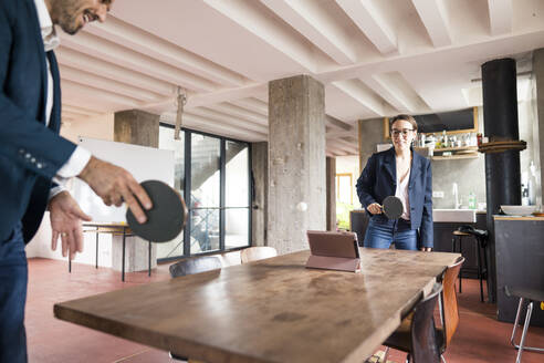 Business people playing table tennis while standing at office - MOEF03566