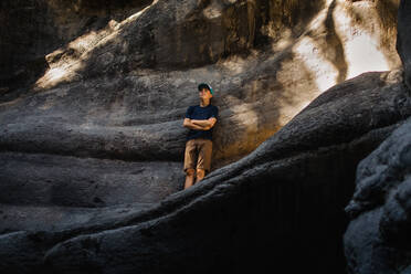 Tens boy leaning up against rock - CAVF90038