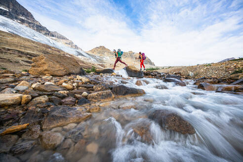 Rucksacktouristinnen überqueren Fluss beim Wandern Schöner Islandpfad - CAVF90119