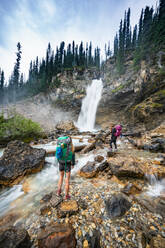 Wanderer stehen neben dem Wasserfall Lachender Wasserfall in Yoho - CAVF90123