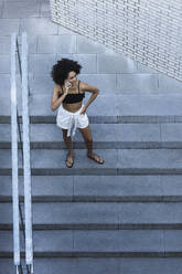 Young woman using smart phone while standing on steps - PNAF00005