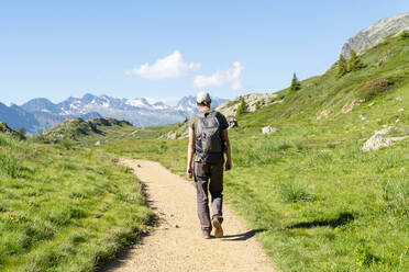 Mittlerer erwachsener Mann beim Wandern in den Bergen an einem sonnigen Tag - GEMF04296