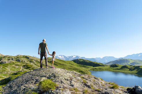 Vater und Tochter stehen auf einem Felsen und betrachten die Aussicht gegen den klaren Himmel - GEMF04304