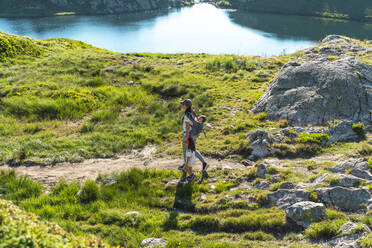 Mutter wandert in den Bergen mit Töchtern an einem sonnigen Tag im Sommer - GEMF04309