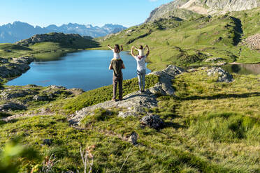 Mutter und Vater, die ihre Töchter auf den Schultern tragen und die Aussicht genießen, während sie an einem sonnigen Tag stehen - GEMF04313