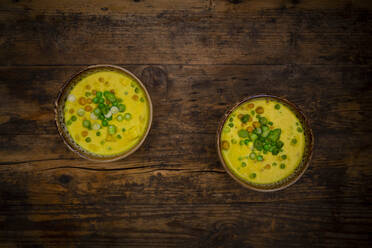 Two bowls of vegan coconut soup with green peas, chick-peas, scallion and turmeric - LVF09067