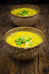 Two bowls of vegan coconut soup with green peas, chick-peas, scallion and turmeric - LVF09068