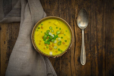 Bowl of vegan coconut soup with green peas, chick-peas, scallion and turmeric - LVF09069