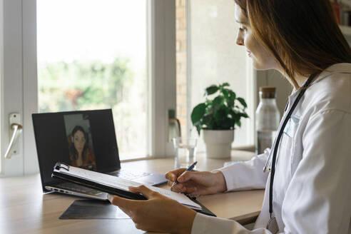 Young female doctor discussing with patient during online consultation - AFVF07382