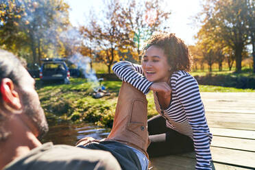 Glückliches junges Paar entspannt auf sonniger Herbstanlegestelle - CAIF29834